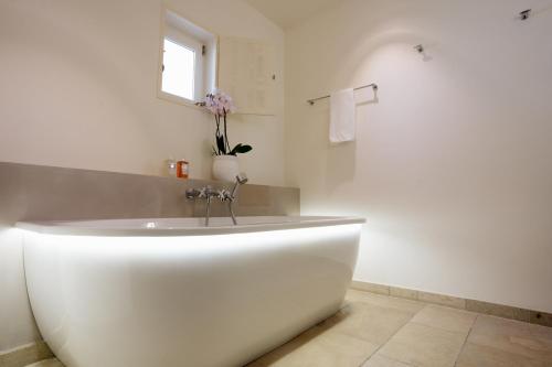 a white bath tub in a bathroom with a window at Coquillade Provence - Relais & Châteaux in Gargas