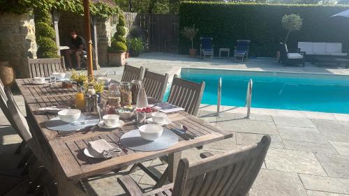a wooden table and chairs next to a pool at Hewletts Mill in Castle Cary