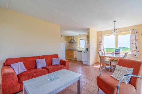a living room with a red couch and a table at Postweg 50 in De Cocksdorp