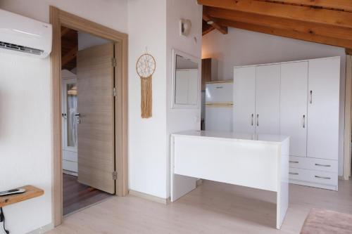 a kitchen with white cabinets and a white table at Your charming sea view penthouse in Çeşme in Cesme