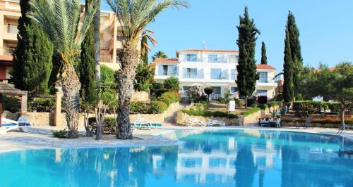 einem großen Pool mit Palmen und einem Gebäude in der Unterkunft Regina Gardens - Modern 2 bed maisonette in Paphos City