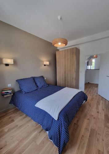 une chambre avec un grand lit avec des draps bleus et blancs dans l'établissement LAGUNE ÉLÉGANTE CENTRE spacieux et à 5 min de la plage, à Dinard
