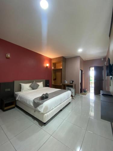 a bedroom with a large bed and a red wall at Grand Village Inn in Pantai Cenang