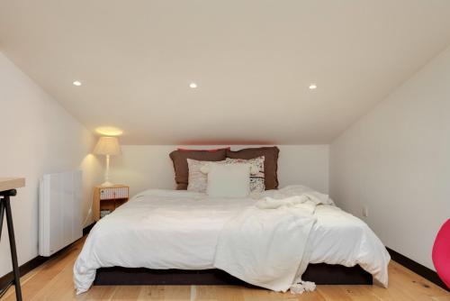 a white bedroom with a large bed with white sheets at Perle rare au coeur de Bordeaux - Bordeauxlidays in Bordeaux