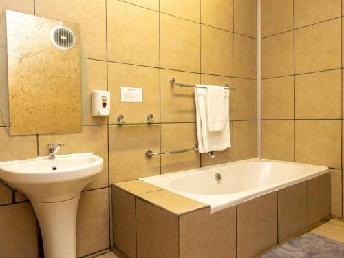 a bathroom with a sink and a bath tub at Ikhutse Manor Guesthouse in Mahikeng