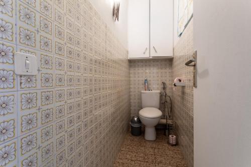 a bathroom with a toilet and a tiled wall at Villa de famille Maragre, au calme in Sainte-Marie-la-Mer