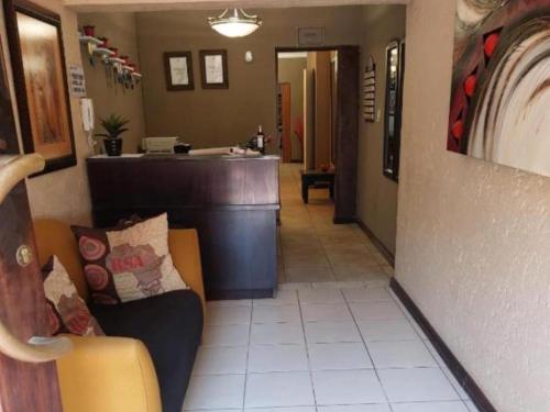 a waiting room with a couch and a bar at Ikhutse Manor Guesthouse in Mahikeng