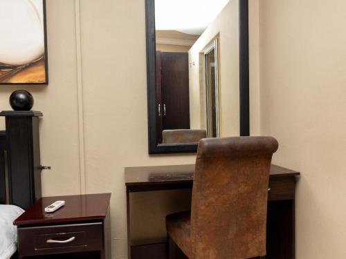 a room with a desk with a chair and a mirror at Ikhutse Manor Guesthouse in Mahikeng