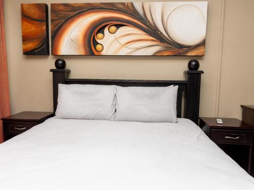 a bedroom with a bed and a painting on the wall at Ikhutse Manor Guesthouse in Mahikeng