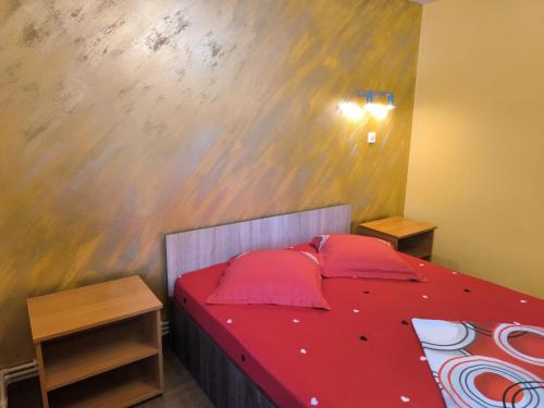 a bedroom with a bed with red sheets and pillows at Casa de vacanță Anni - 2 min de piață in Eforie Nord