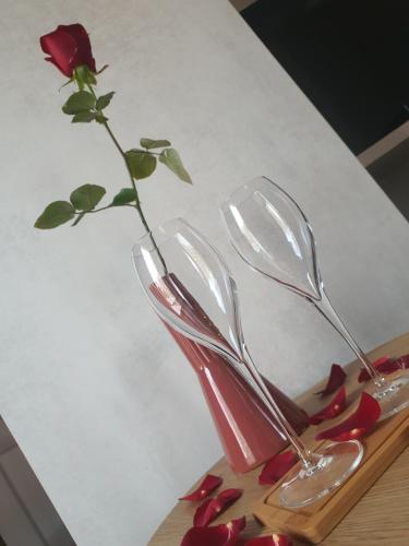 a red vase with a rose in it on a table at Suite Terracotta : Gîte de charme en Avesnois in Wargnies-le-Grand