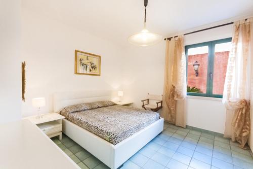 a white bedroom with a bed and a window at Casa Vacanze Villa Flumini in Flumini di Quartu