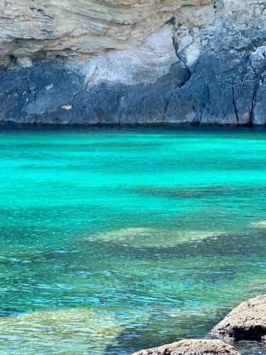 a large body of blue water next to a cliff at La Tavernetta del Salento in Poggiardo