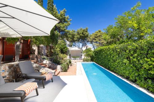 a pool with chairs and an umbrella next to a house at Villa Gallus - Jelsa, Hvar in Jelsa