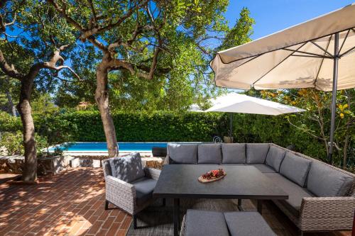 a patio with a couch and an umbrella at Villa Gallus - Jelsa, Hvar in Jelsa