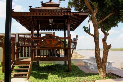 a gazebo with a bench and a tree at Mekong Tarawadee Villa in Tha Bo