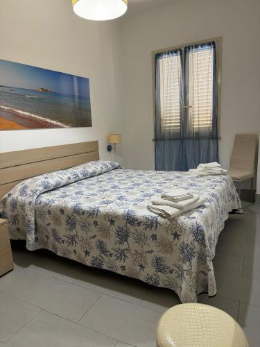 a bedroom with a bed with a blue and white blanket at Casa Vacanze Il Borghetto in Marzamemi