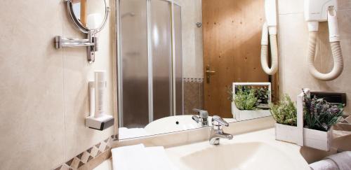 La salle de bains est pourvue d'un lavabo et d'un miroir. dans l'établissement Hotel Comfort Erica Dolomiti Val d'Adige, à Salorno