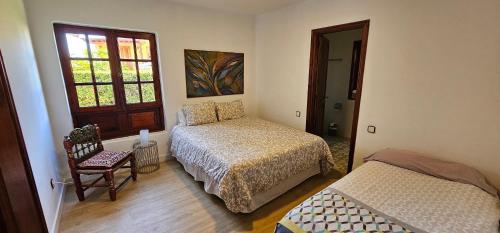 a bedroom with two beds and a chair and a window at Villa la Paz in Puerto de la Cruz