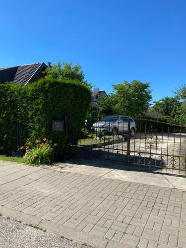 a fence with a hedge and a car in a parking lot at „Sėlių Studio“ Apartamentai in Utena