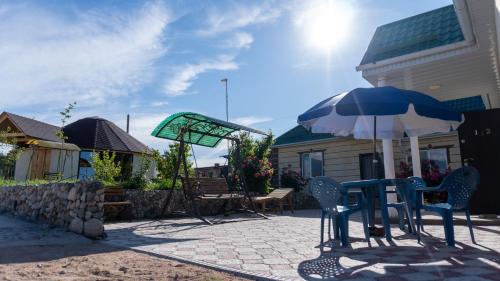 a patio with a table and an umbrella at Guest house and yurt camp Svetlana in Bokonbayevo