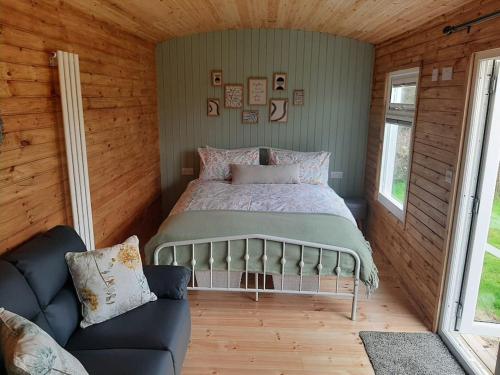 a bedroom with a bed and a couch in a room at Anglesey new modern shepherds hut with spa hot tub in Gwalchmai