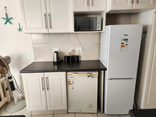 a kitchen with white cabinets and a white refrigerator at Driftsands Sea View Flats in Uvongo Beach