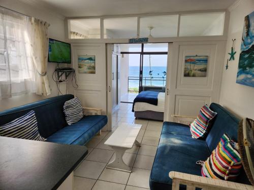 a living room with blue couches and a bedroom at Driftsands Sea View Flats in Uvongo Beach