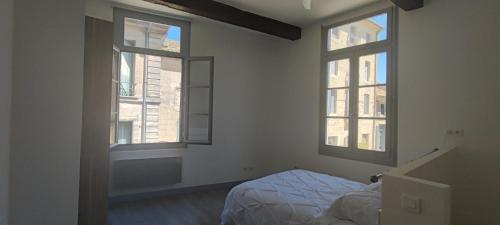 a bedroom with two windows and a bed in it at L'Echauguette d'Uzès by Les Demeures de Rachel in Uzès