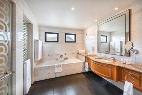 a bathroom with a tub and a sink and a mirror at Labourdonnais Waterfront Hotel in Port Louis