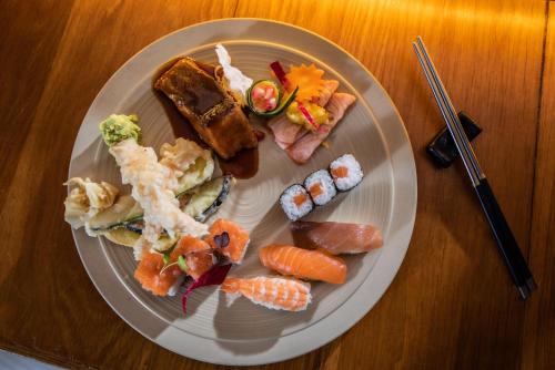 a plate of food with sushi on a wooden table at Hennessy Park Hotel in Ebene