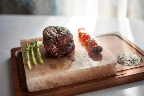 a cutting board with a steak and vegetables on it at Labourdonnais Waterfront Hotel in Port Louis