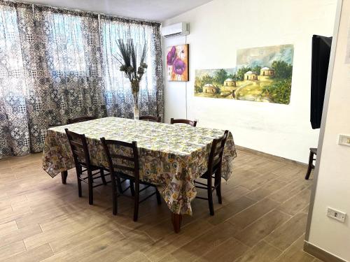 a dining room table with chairs and a vase with flowers at Case vacanze ''Estremo Sud'' Lampedusa in Lampedusa
