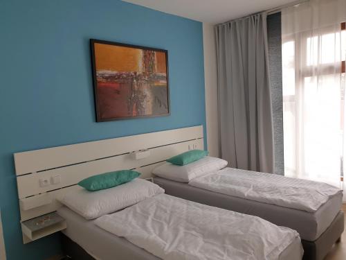two beds in a room with a blue wall at Ubytování Láskomina in Pacov