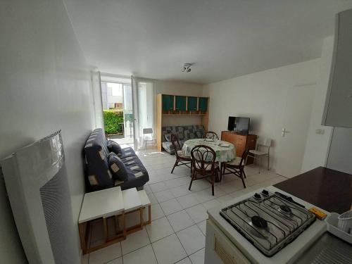 Il dispose d'une cuisine et d'un salon avec un canapé et une table. dans l'établissement Studio cosy avec jardin, proche plage et commerces - FR-1-324A-5, à Saint-Hilaire-de-Riez