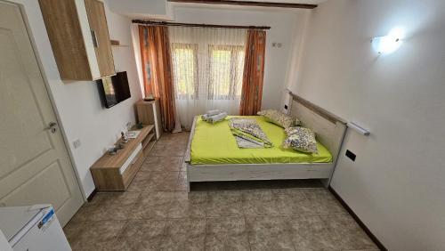 a small bedroom with a bed with a green blanket at Pensiunea Darius Costinesti in Costinesti