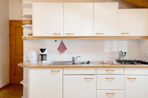 a kitchen with white cabinets and a sink at Friedheim Appartments in Sarntal