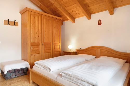 a bedroom with two beds and a wooden cabinet at Friedheim Appartments in Sarntal