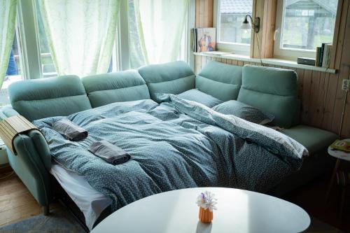 a blue couch in a living room with a bed at Cozy beach cottage in Vääna-Jõesuu