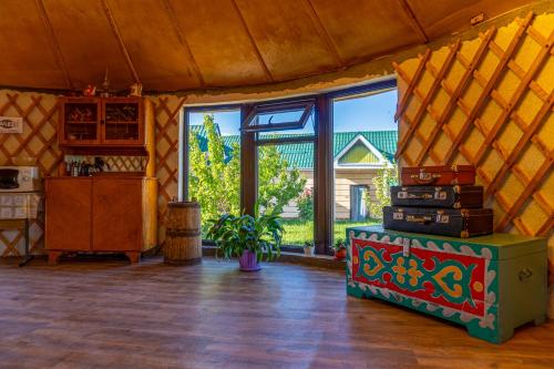 a living room with a table and some windows at Guest house and yurt camp Svetlana in Bokonbayevo