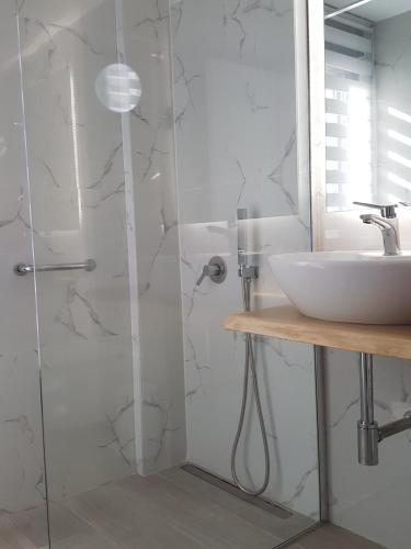 a white bathroom with a sink and a shower at Boutique apartments Myesis in Samothráki