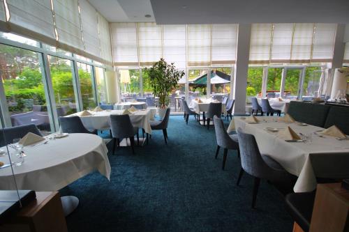 a restaurant with white tables and chairs and windows at Apartmenthaus Haus Sonne I direkt am Strand in Dierhagen