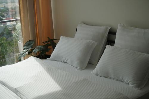 a bed with white sheets and pillows next to a window at Домик 2 Kok Tobe Village in Almaty