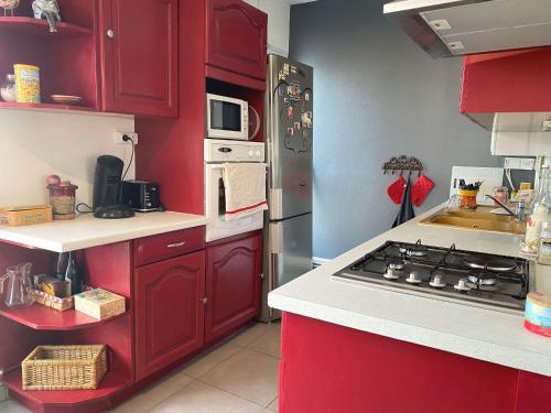 La cuisine est équipée de placards rouges et d'un four avec plaques de cuisson. dans l'établissement Appartement T2 - Balcon, Ascenseur, WIFI, tout équipé à Balaruc-les-Bains - FR-1-553-225, à Balaruc-les-Bains
