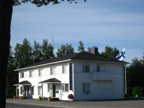 a white building with a flag on top of it at Guesthouse Golden Goose in Kittilä