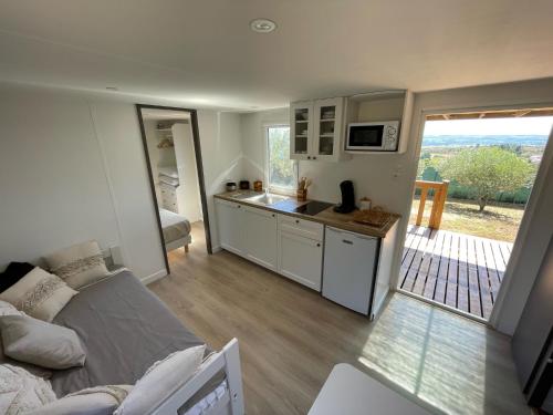 un salon avec un canapé et une cuisine dans l'établissement Mobil-home en pleine nature à 3 mins du Lac du Salagou avec vue panoramique, à Lacoste