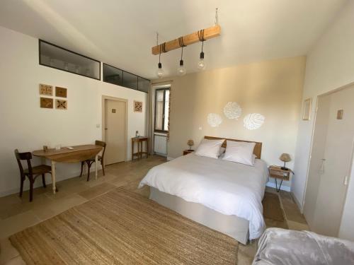 une chambre avec un lit blanc et une table dans l'établissement Le mas de Marie, à Taulignan