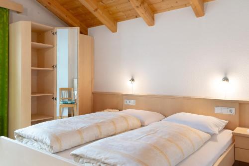 two beds in a room with wooden ceilings at Friedheim Appartments in Sarntal
