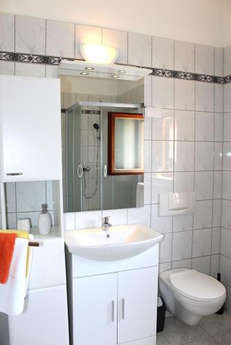 a white bathroom with a sink and a toilet at Sunce in Mali Lošinj