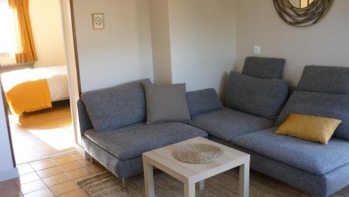 ein Wohnzimmer mit zwei blauen Sofas und einem Tisch in der Unterkunft Chez Caroline in Rainneville
